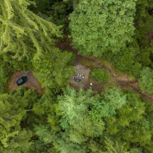 Zelt und Feuerstelle mitten im Wald aus der Vogelperspektive 