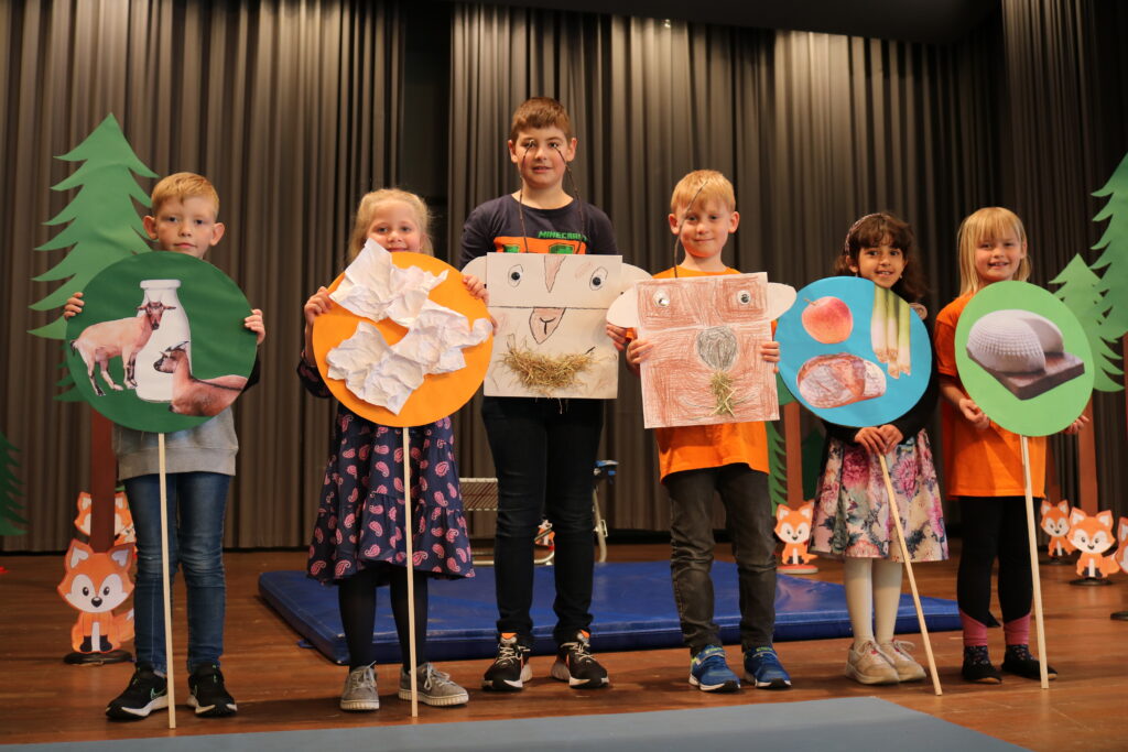 Kinder stehen nebeneinander und halten selbst gebastelte Plakate hoch