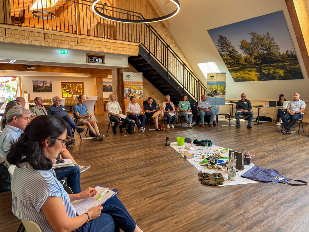 Menschen sitzen in einem großen Raum in einem Halbkreis