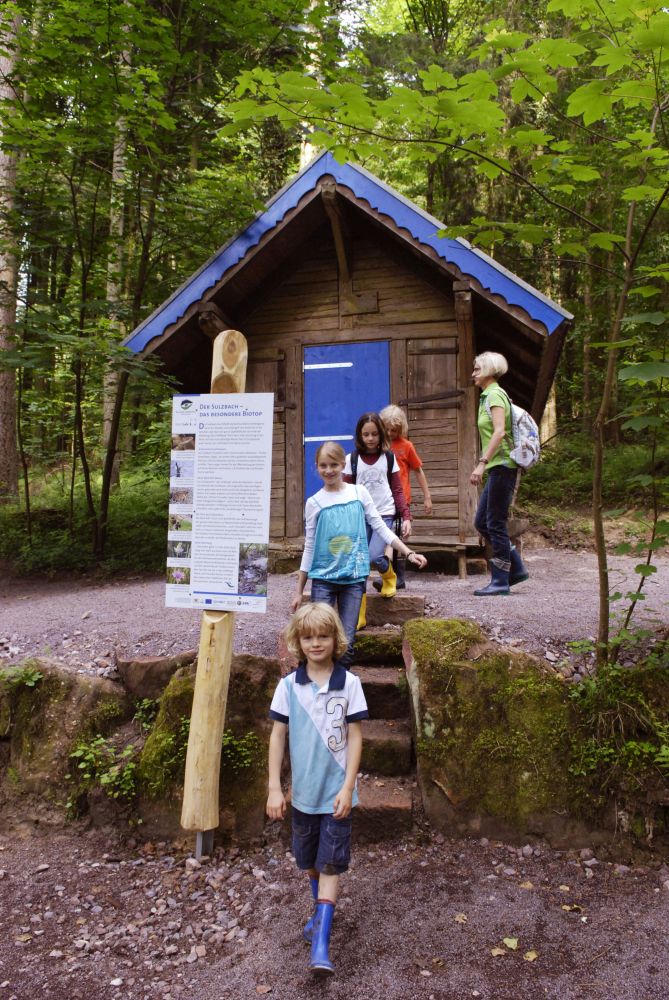 Kinder vor einer Holzhütte im Wald