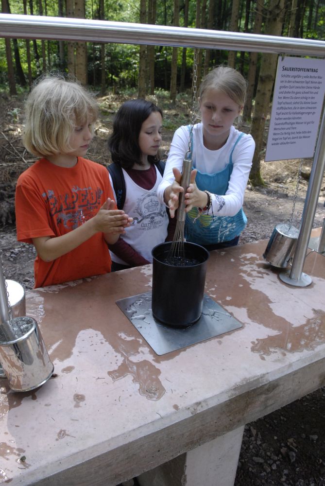 Kinder spielen bei einer Wasser-Station.