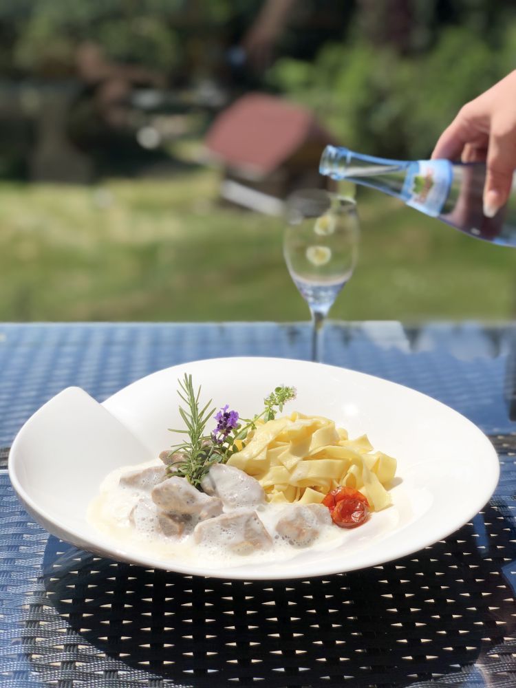 Bandnudeln und Fleischstücke mit heller Soße in einem Teller