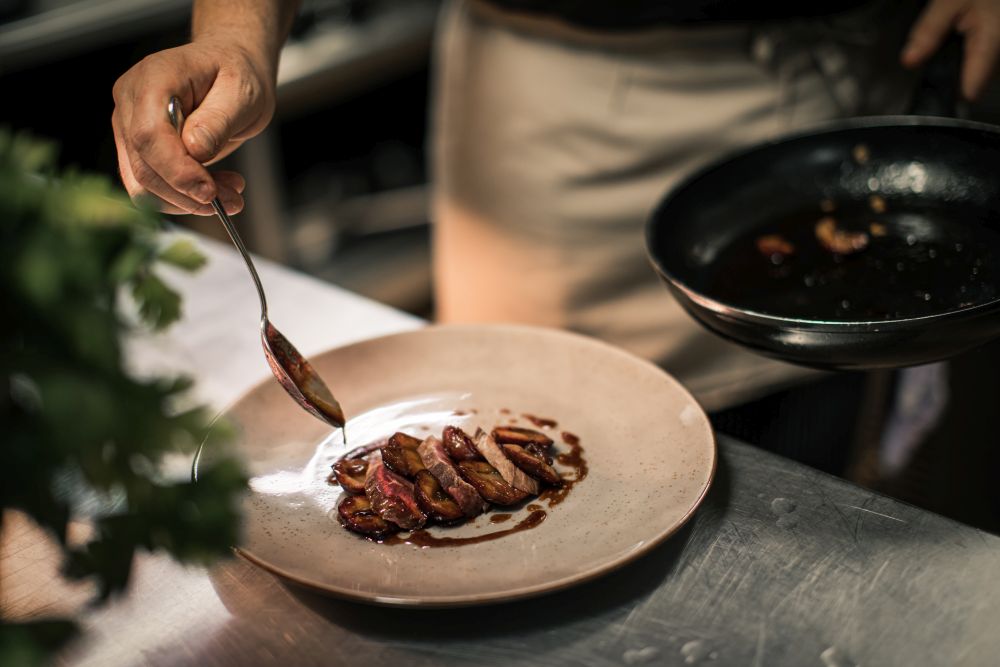 Fleischscheiben werden mit Soße auf einem Teller angerichtet