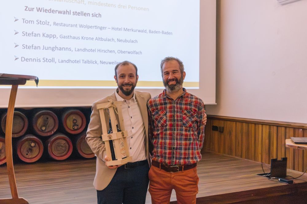 Stefan Junghanns übergibt Patrick Herrmann eine Weinflasche