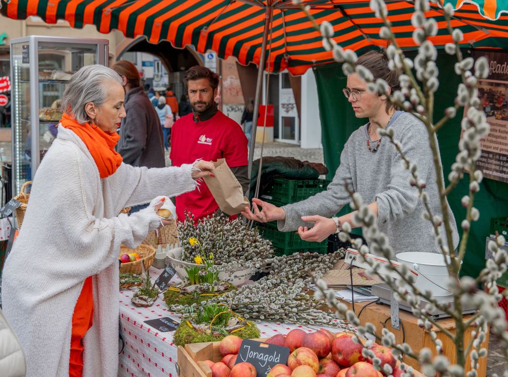 Eine Frau nimmt eine Papiertüte mit gekauften Produkten von einem Marktbeschicker in Empfang.