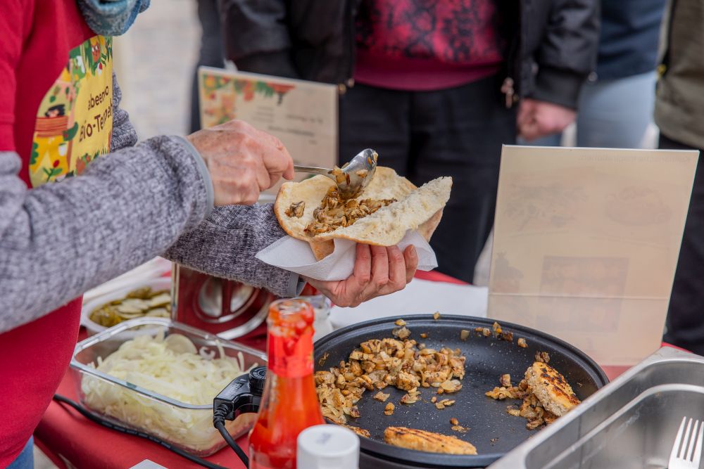 Tempeh wird aus der Pfanne in ein Fladenbrot portioniert.