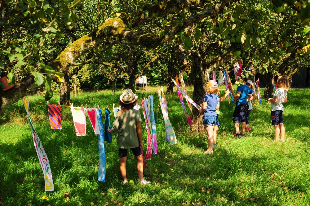 bunte Stoffstücke sind auf einer Leine zwischen Streuobstbäumen gespannt.