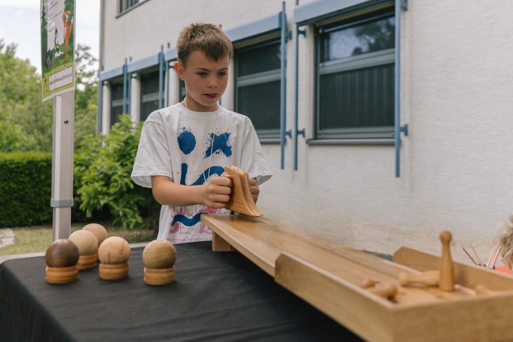 Ein Junge schießt eine Holzkugel in Richtung Kegel.
