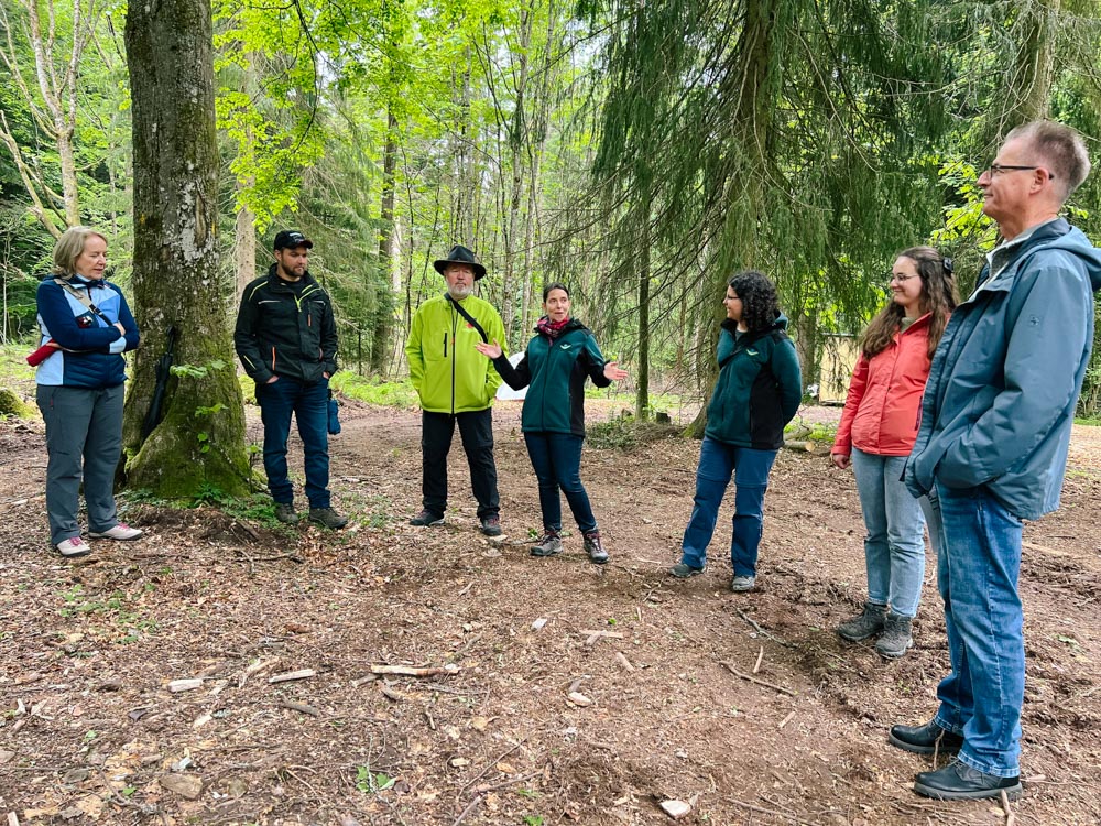Menschen stehen bei Camp-Eröffnung im Wald
