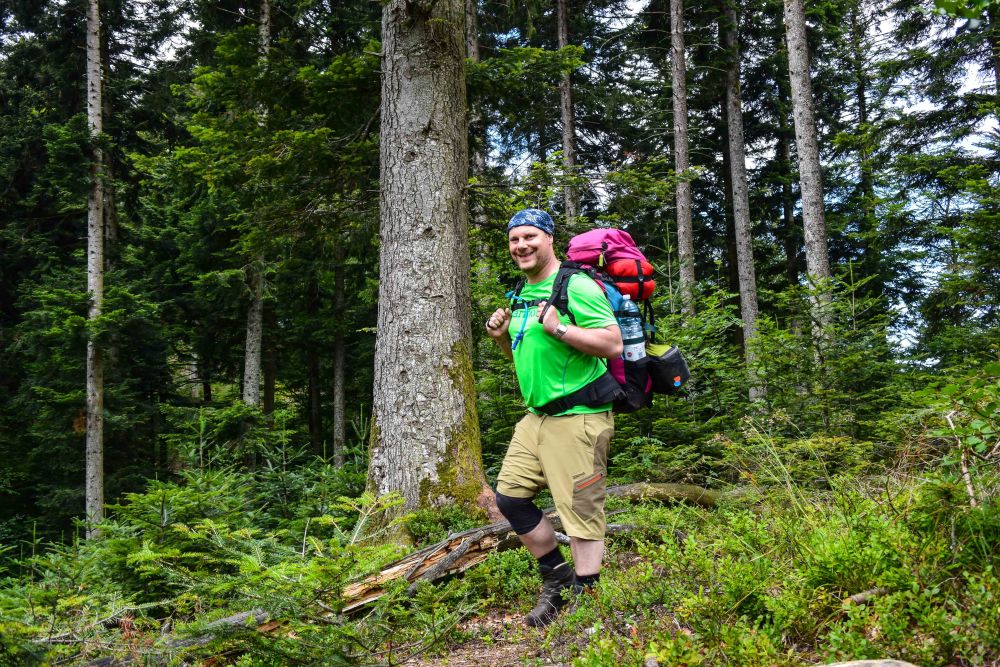Ein Mann wandert mit Trekking-Rucksack durch den Wald.