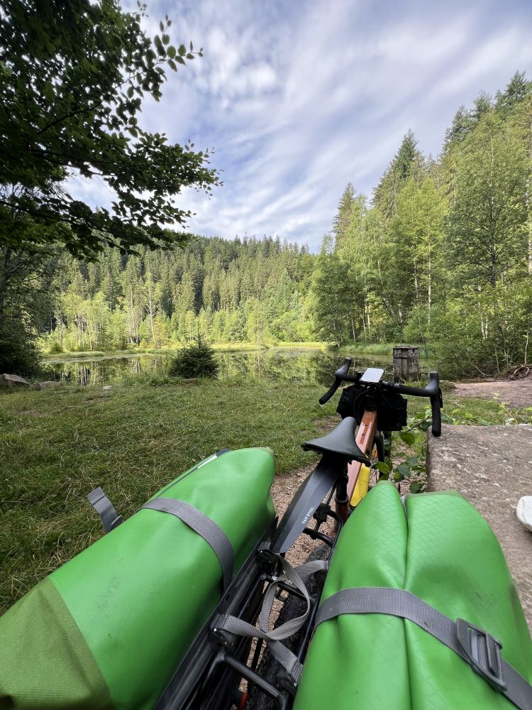 Gravel Bike mit Trekking-Taschen steht vor einem Karsee im Schwarzwald.