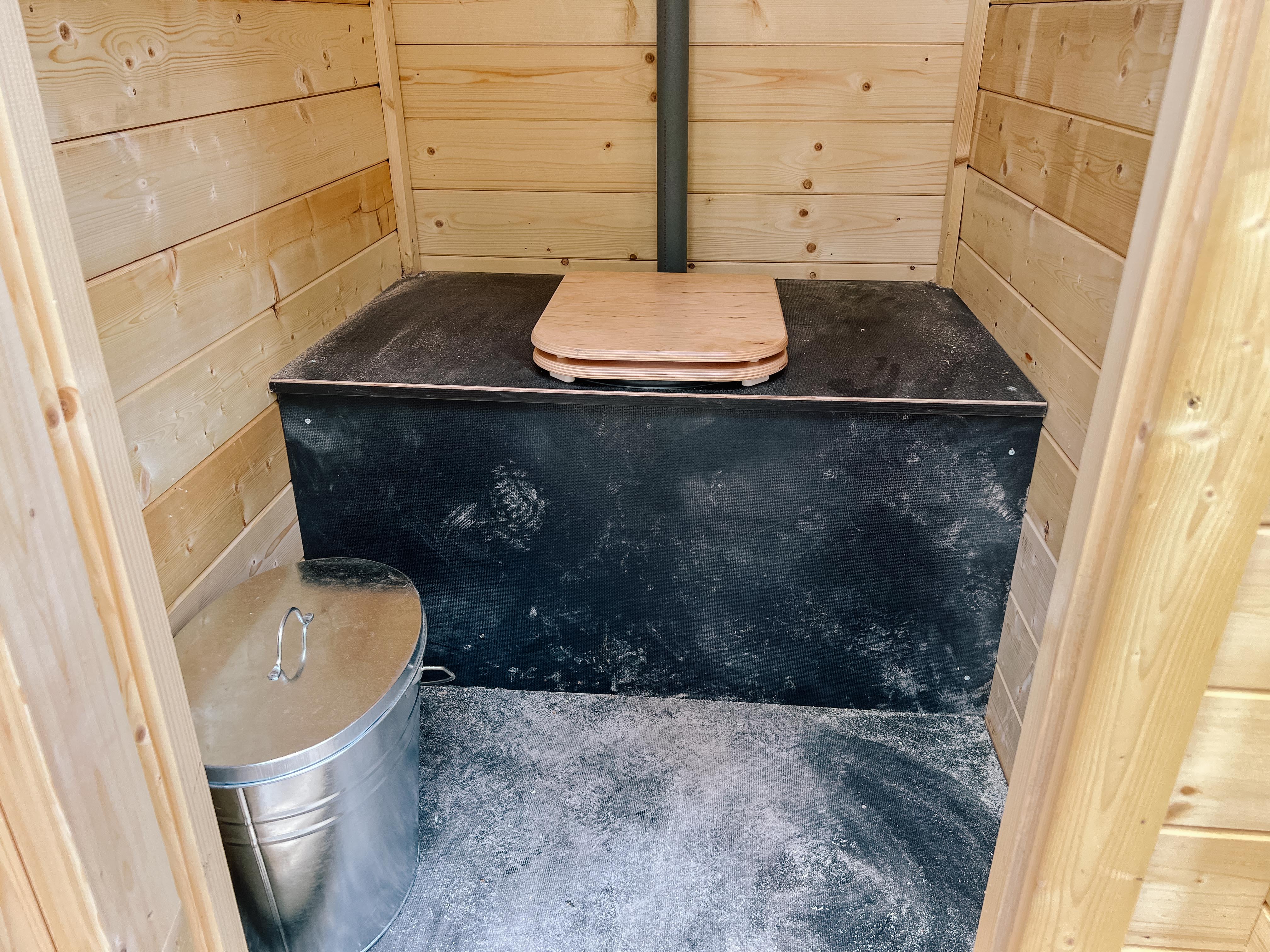 Plumpsklo in hölzernem Toilettenhäuschen
