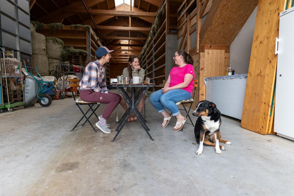 Beim Gespräch am Tisch im Stall: Gundi Woll, Irmela Klöble und Nadine Göz mit Hund