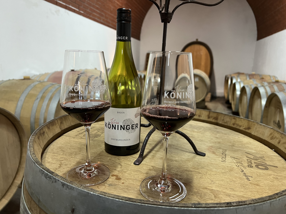 Weinflasche auf Eichenfass mit zwei mit Rotwein gefüllten Gläsern