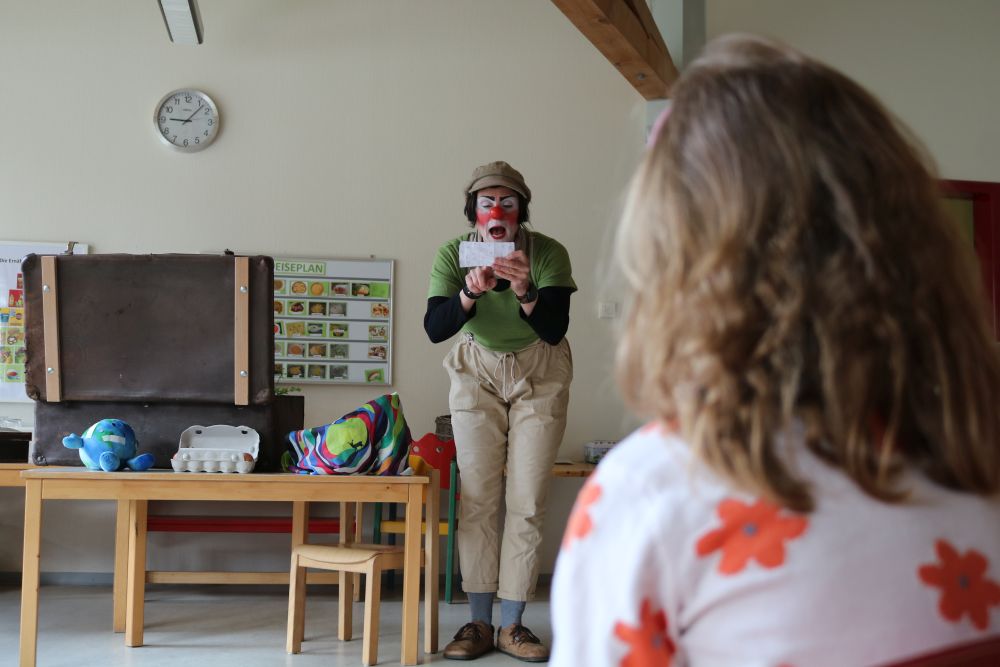 Clownin liest Kindern etwas vor.
