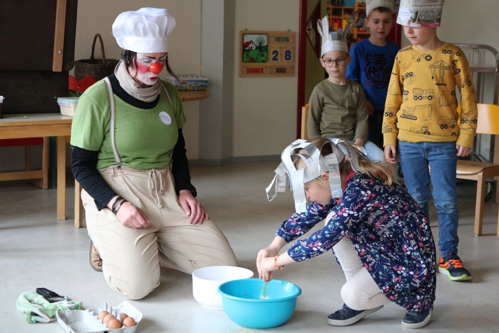 Ein Mädchen schlägt ein Ei über einer Schüssel auf.