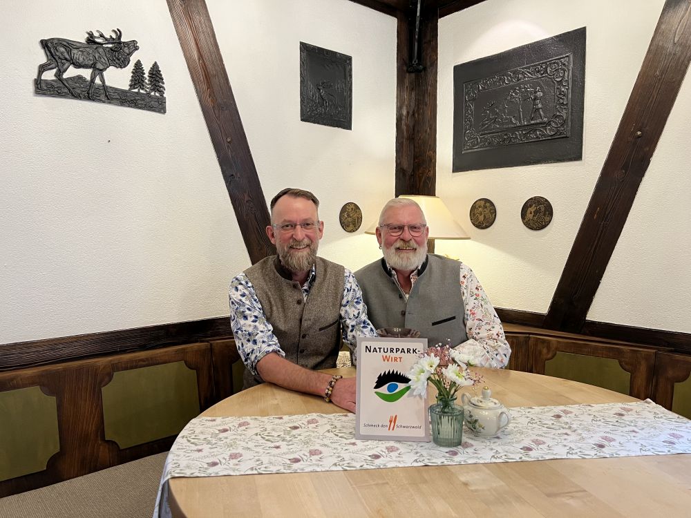 Arno Peiffer (l.) und Ralf Bischoff (r.) präsentieren an ihrem Lieblingsplatz in ihrem Landcafé Baiermühle in Altensteig die Auszeichnung als „Naturpark-Wirt“ – ein Prädikat für regionale Küche.