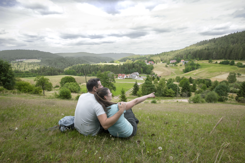 AugenBlick Lauterbach, Pärchen sitzt auf einer Wiese und blickt auf Wald, Weiden, Wiesen