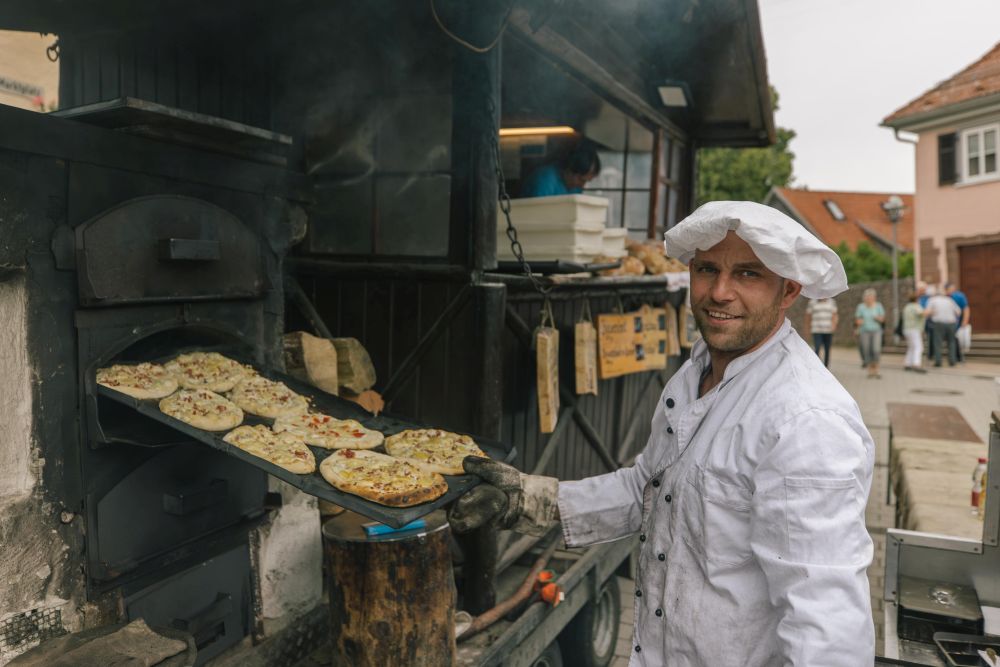 Mann schiebt Dinnede in einen Holzofen.