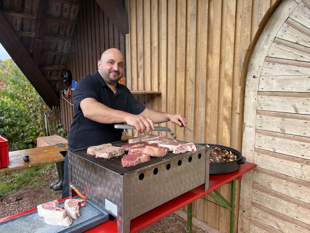 Metzger brät Schweinefleisch auf einem Grill.