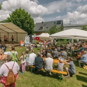 Gäste sitzen auf Bänken und schauen dem Auftritt einer Tanzgruppe zu.