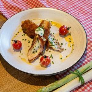 Spargel-Cordonbleu mit Tomaten und Sahnesoße auf einem Teller
