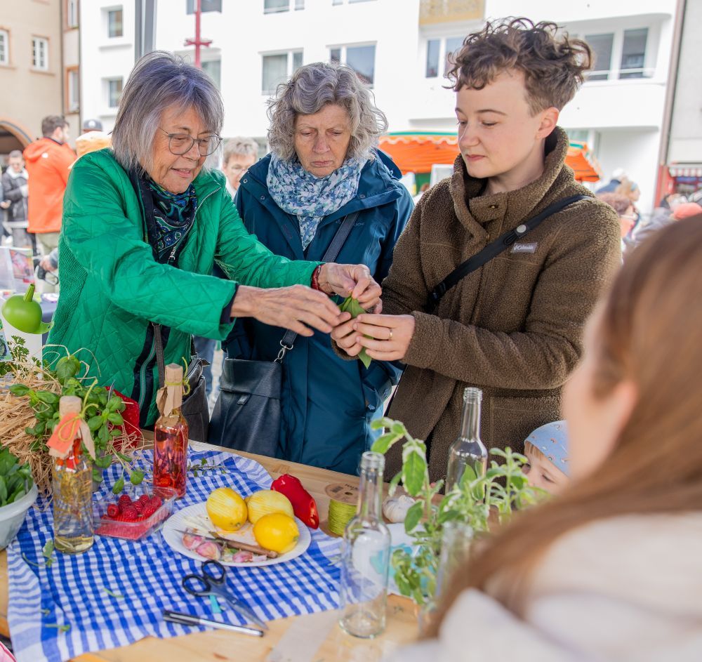 Drei Frauen schauen sich einen Marktstand an.