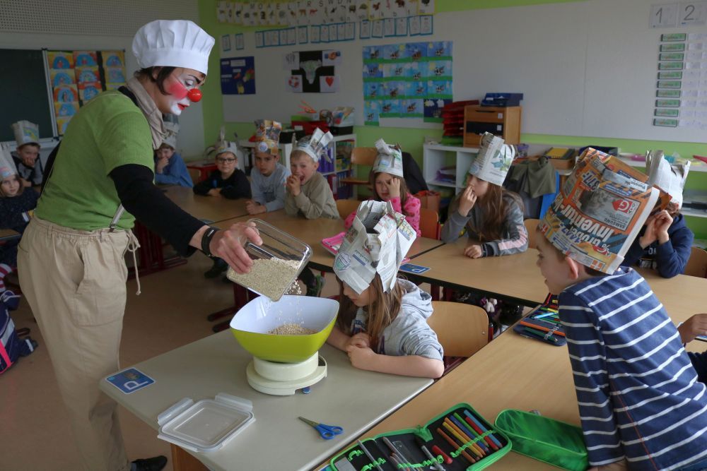 Die Clownin füllt Haferflocken in eine Schüssel auf einer Waage.