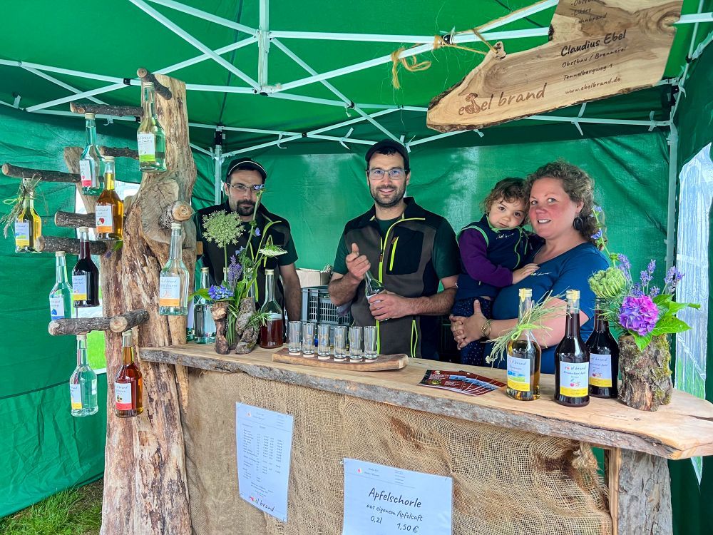 Markt-Stand eines Schnapsbrenners mit Familie und Produkten