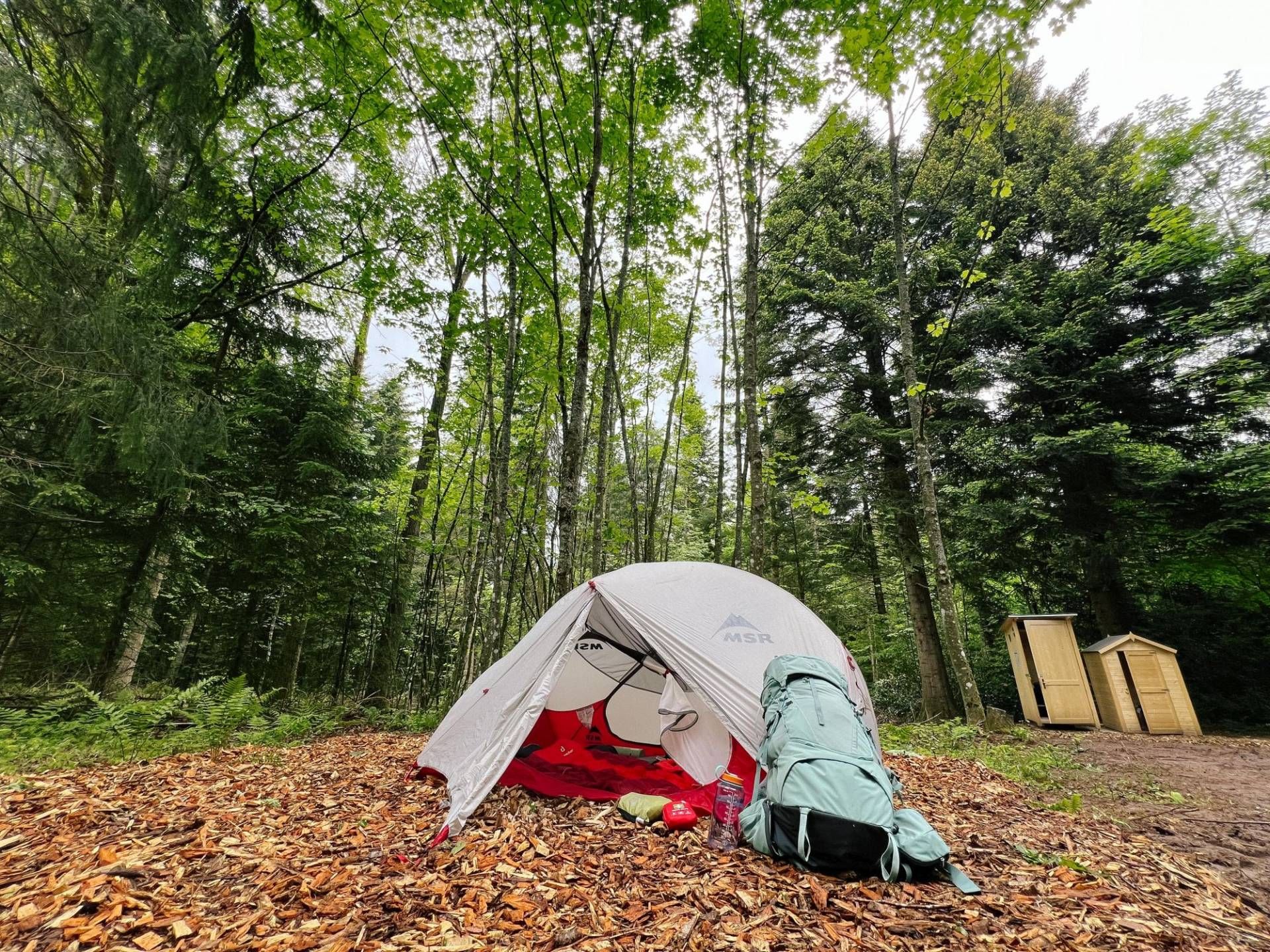 Zelt mit Trekking-Rucksack im Wald