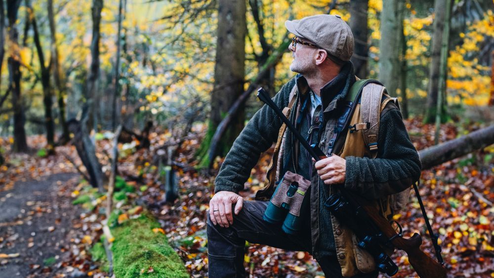 Jäger Tom Stolz mit Gewehr im Wald. 