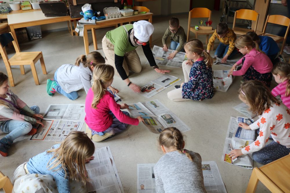 Kinder basteln mit Zeitungen.