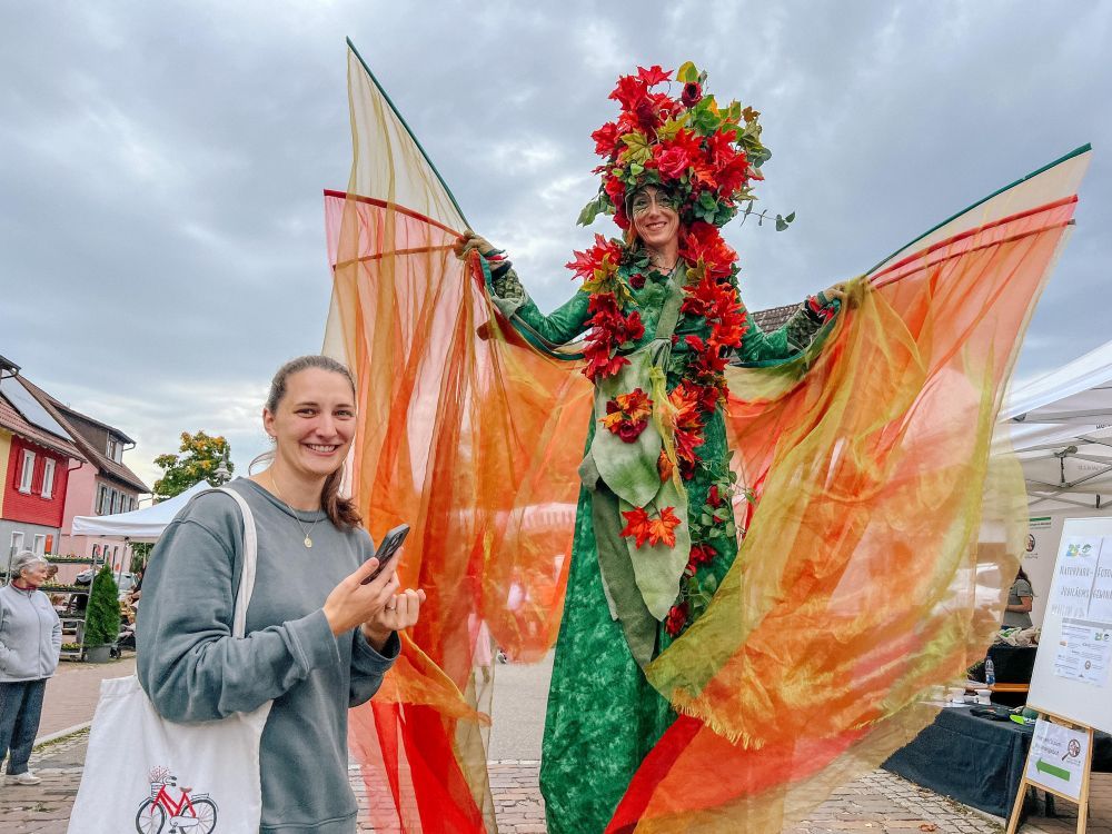 Eine Frau auf Stelzen hat sich als Blumenfee verkleidet