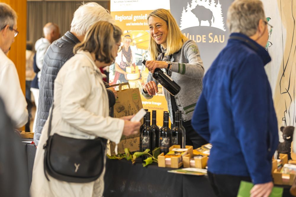 Eine Frau schenkt Besuchern Wein aus.