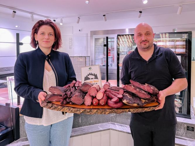 Judith Wohlfahrt und Alexander Ehret halten ein großes Holzbrett mit Wilde Sau-Spezialitäten und der Wilde Sau-Partnerplakette in den Händen.