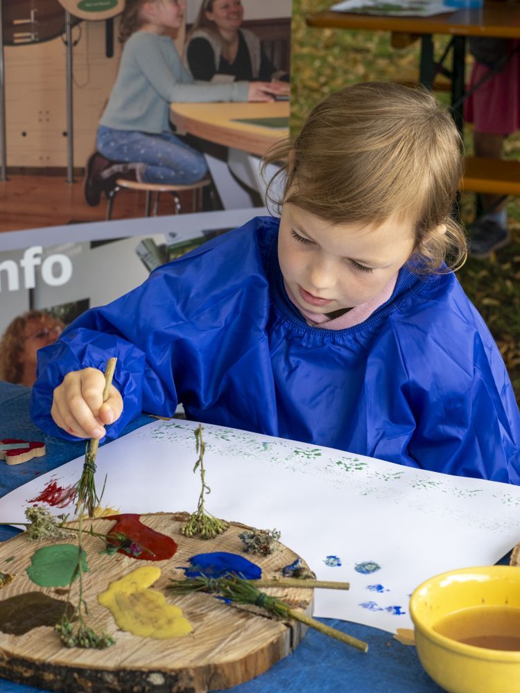 Kind malt mit einem Naturpinsel.