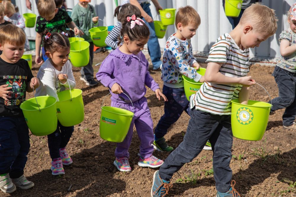 Kinder bringen Saatgut auf einer Fläche aus.