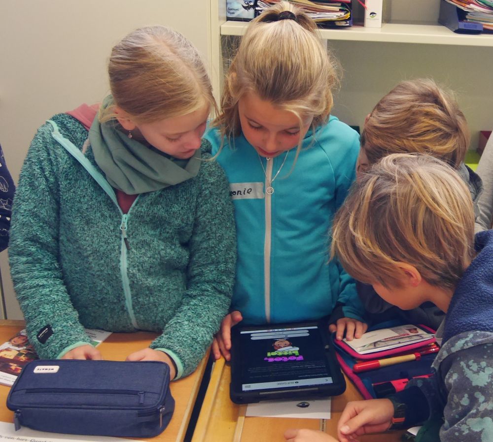 Kinder lösen eine Aufgabe auf einem Tablet.