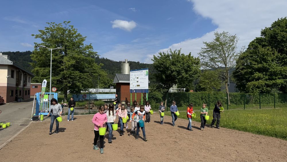 Kinder bringen Saatgut auf der Fläche aus.