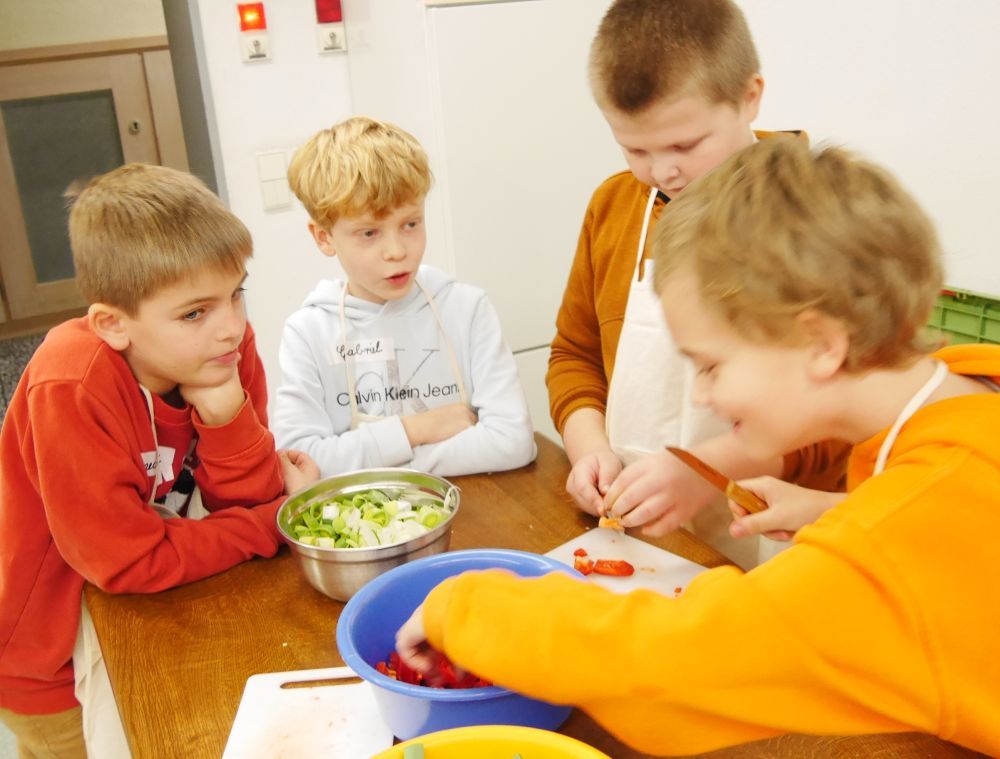 Jungs unterhalten sich beim Gemüse-Schnippeln.