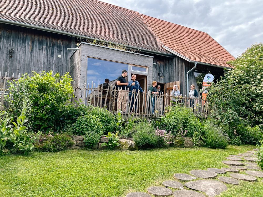 Menschen unterhalten auf der Holzterrasse vor der Dorfscheune