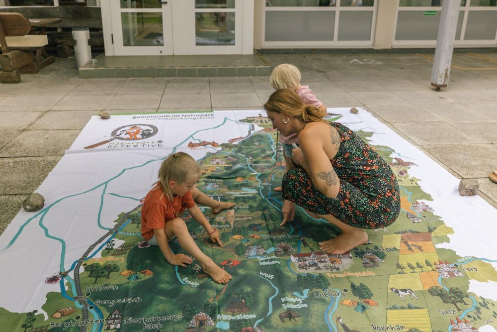 Eine Frau schaut mit Kindern die Naturpark-Karte an.