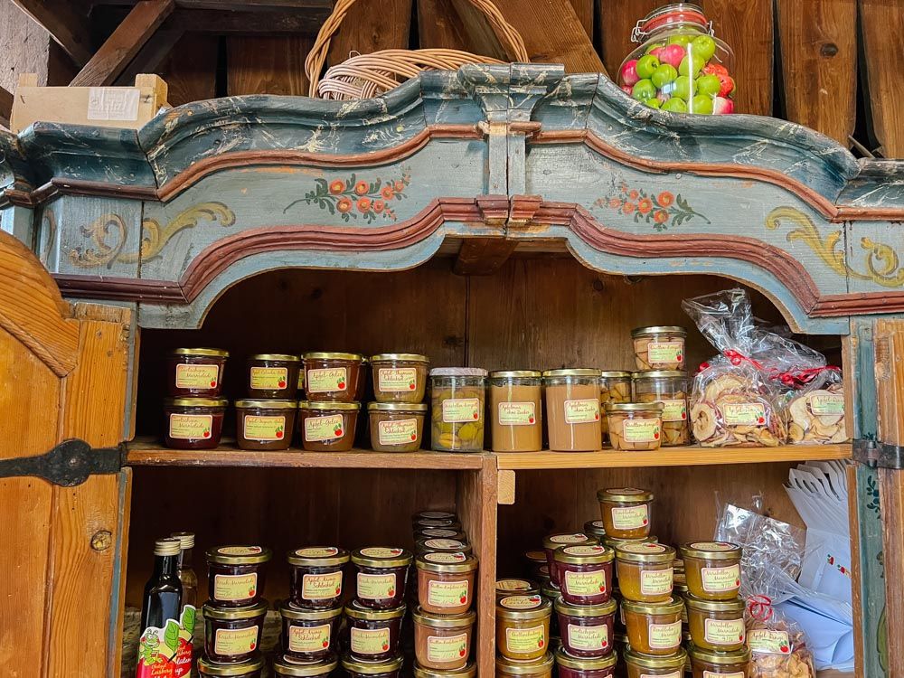 Streuobstprodukte wie Marmeladen im Glas stehen in einem offenen Schrank in einer Scheune