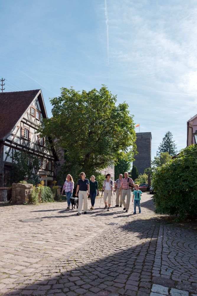 Familie wandert durch ein Dorf an einem Fachwerkhaus vorbei.