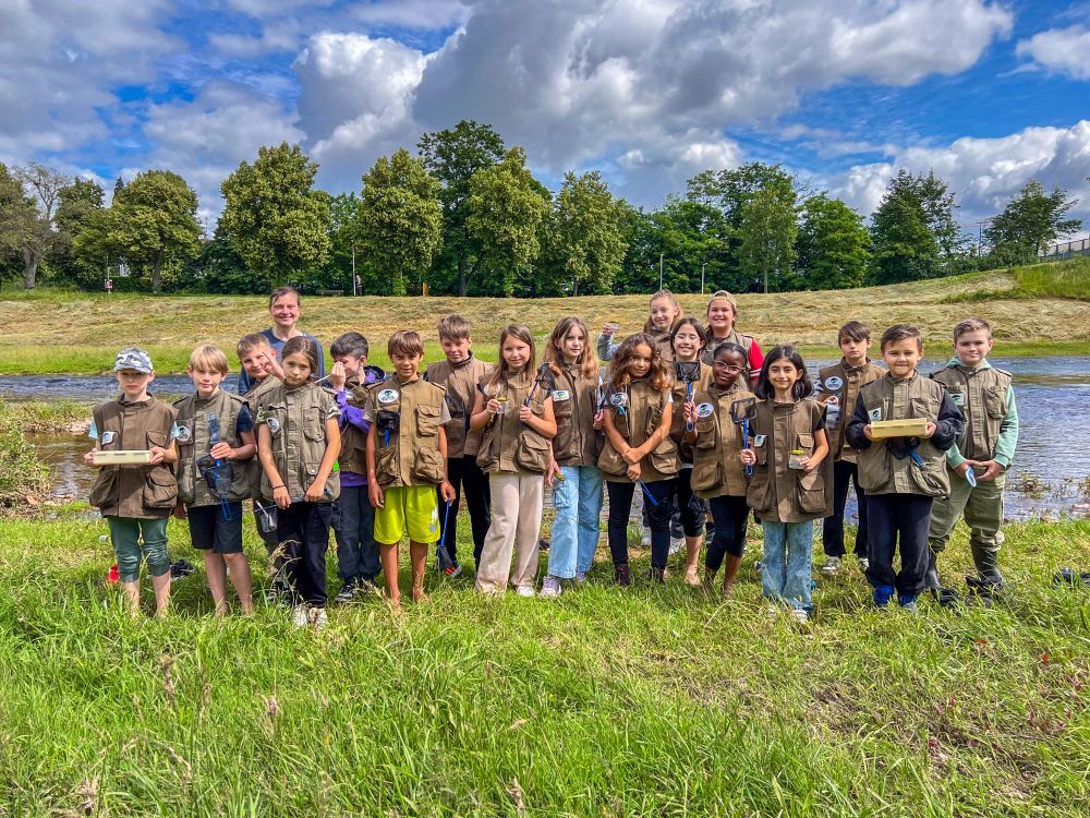 Eine Schulklasse steht als Gruppe zusammen vor der Murg mit den Naturpark-Entdeckerwesten