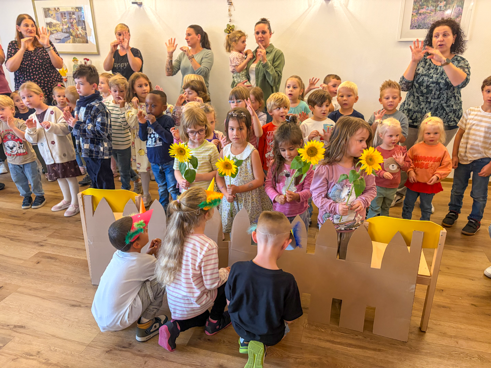 Kinder bei der Aufführung mit Sonnenblumen und mit Vogelschnabel