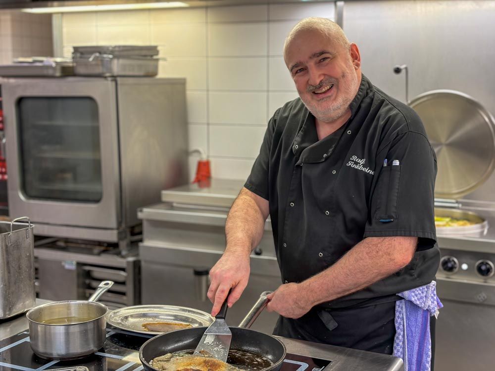 Küchenchef wendet ein Forellenfilet in der Pfanne