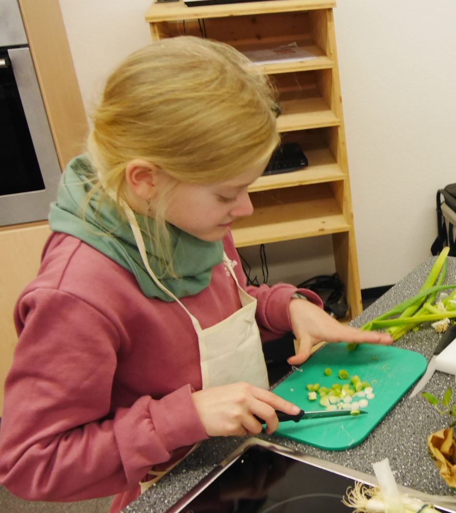Ein Mädchen schnippelt Gemüse.
