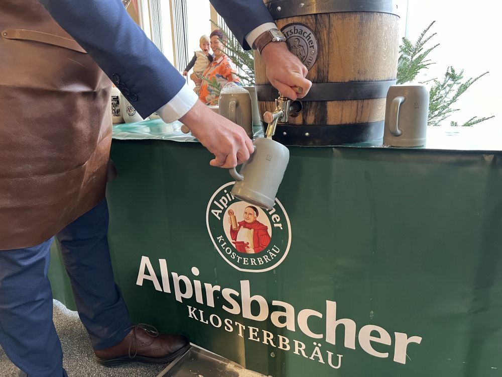 Ein Mann zapft Bier aus einem Holzfass von Alpirsbacher Klosterbräu.