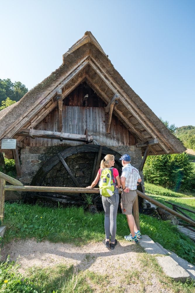 Paar steht vor einem kleinen Mühlrad.